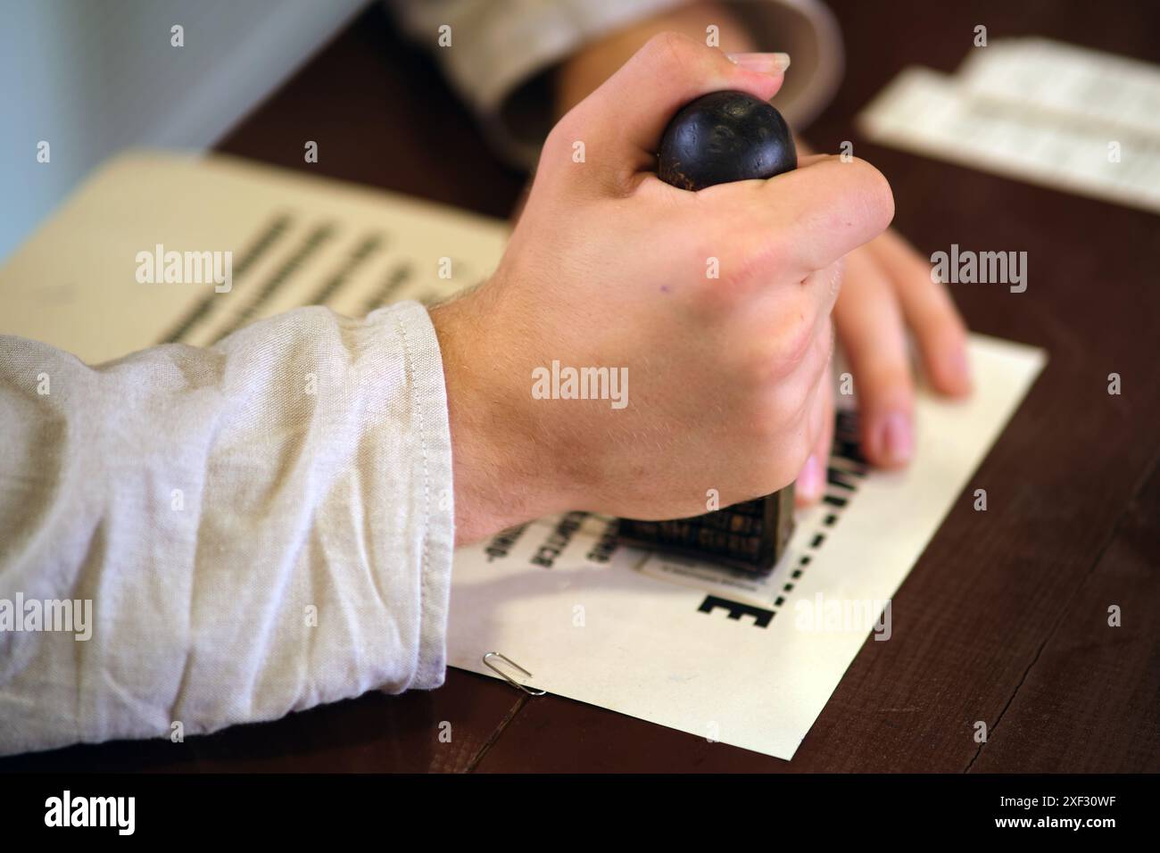 La main d'un homme met un sceau sur un morceau de papier, gros plan Banque D'Images