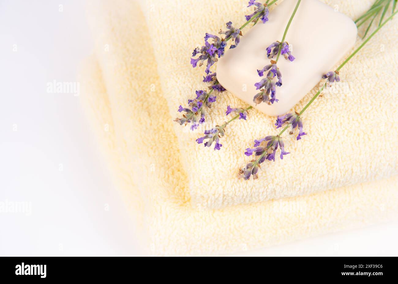 Une pile de serviettes blanches douces avec des fleurs de lavande et une barre blanche de savon sur le dessus, créant une atmosphère de spa. Banque D'Images