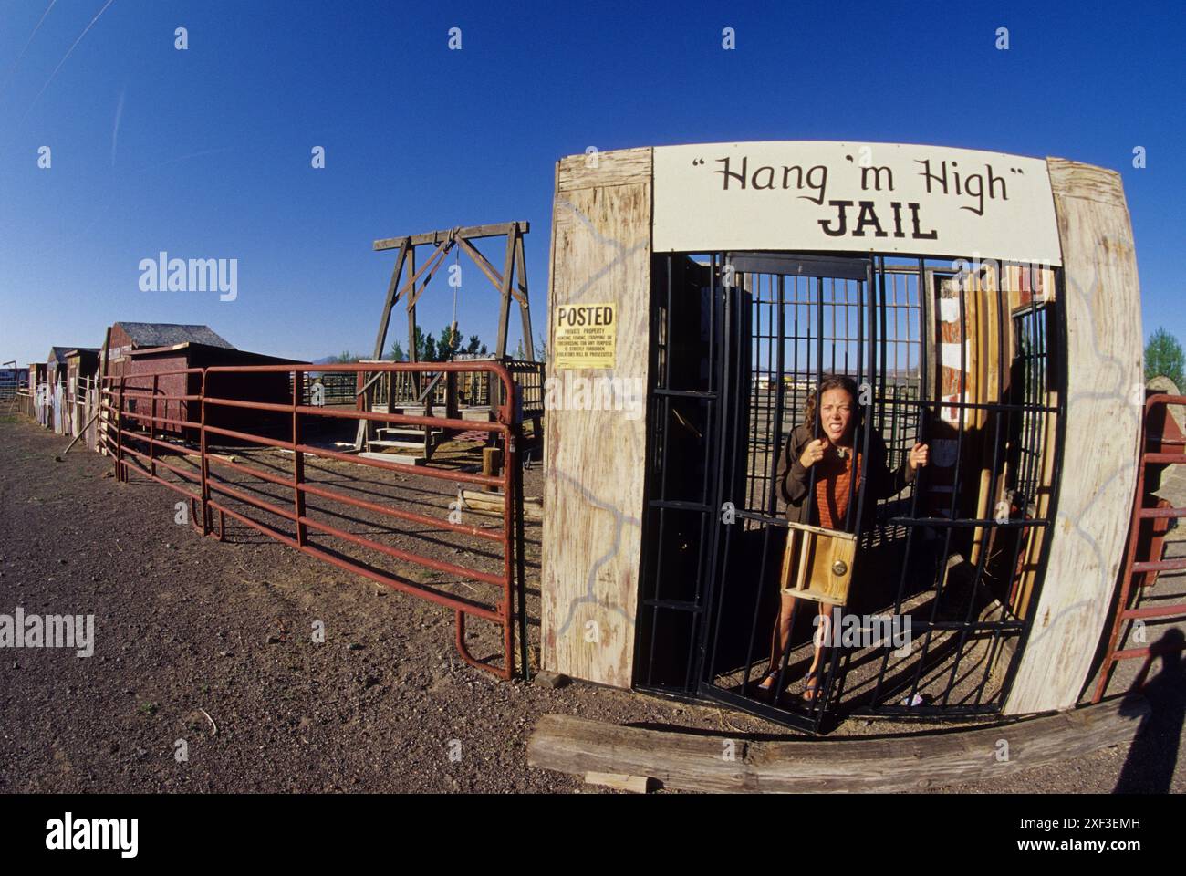 Une femme dans une ville à thème occidental derrière de vieux bars de prison. Banque D'Images