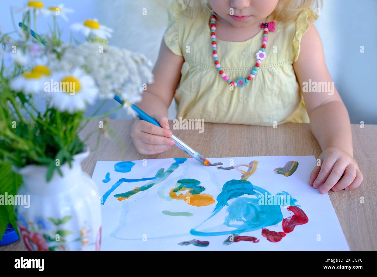 peintures à la main pour enfants avec pinceau, petit enfant, petite fille préscolaire 3 ans crée une image lumineuse sur papier, dessin naïf enfantin en wat coloré Banque D'Images