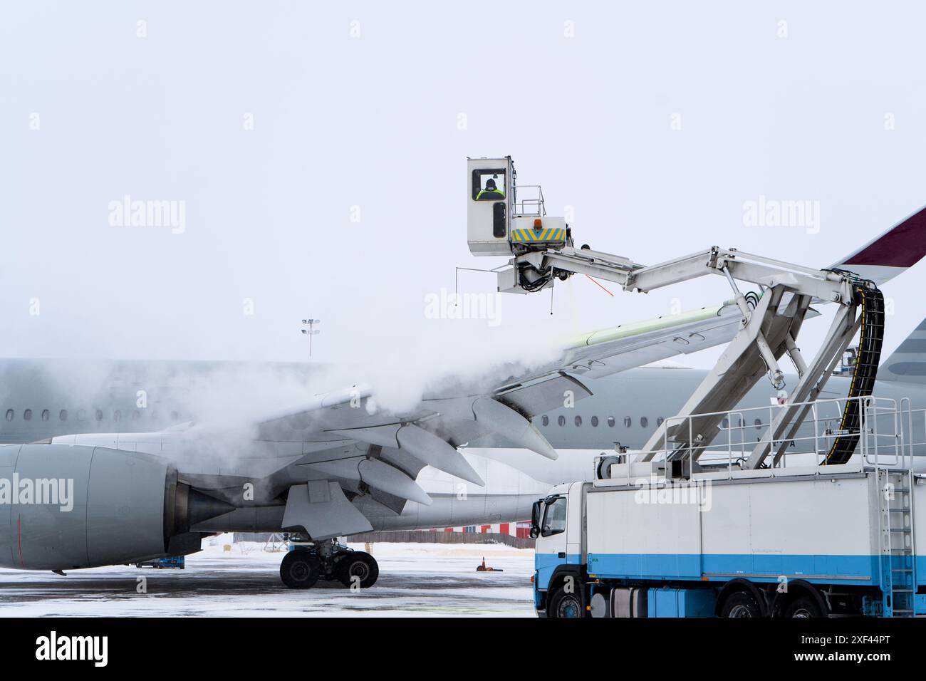 Dégivrage de l'avion avant le vol. La machine de dégivrage saupoudre l'aile d'un avion de passagers d'antigel. Hiver à l'aéroport. Neige. Manutention aérienne. Vapeur dans le froid. Service aéroport Banque D'Images