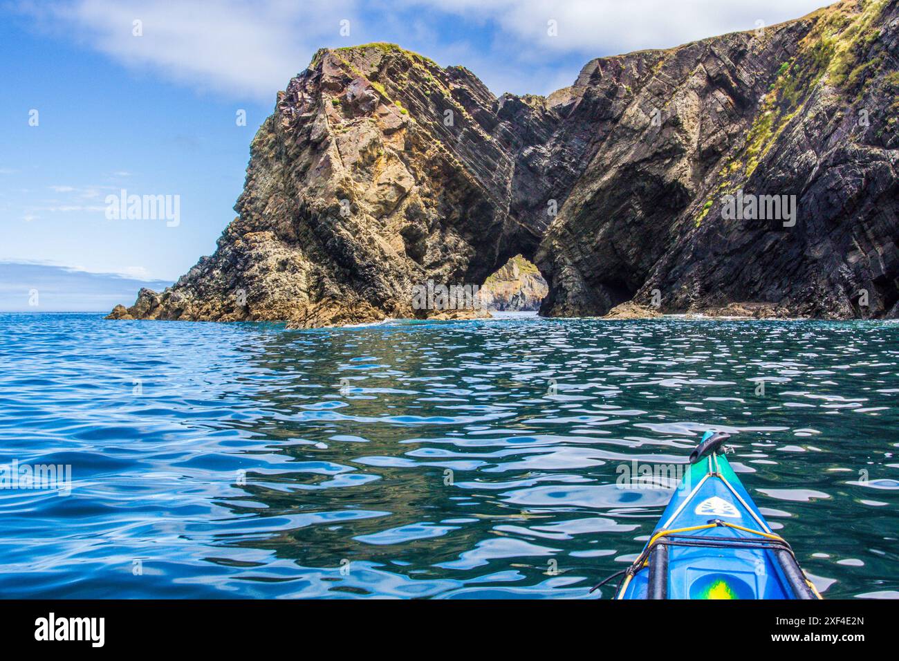 Kayak de mer vers une arche naturelle sur la côte du Pembrokeshire dans l'ouest du pays de Galles Banque D'Images