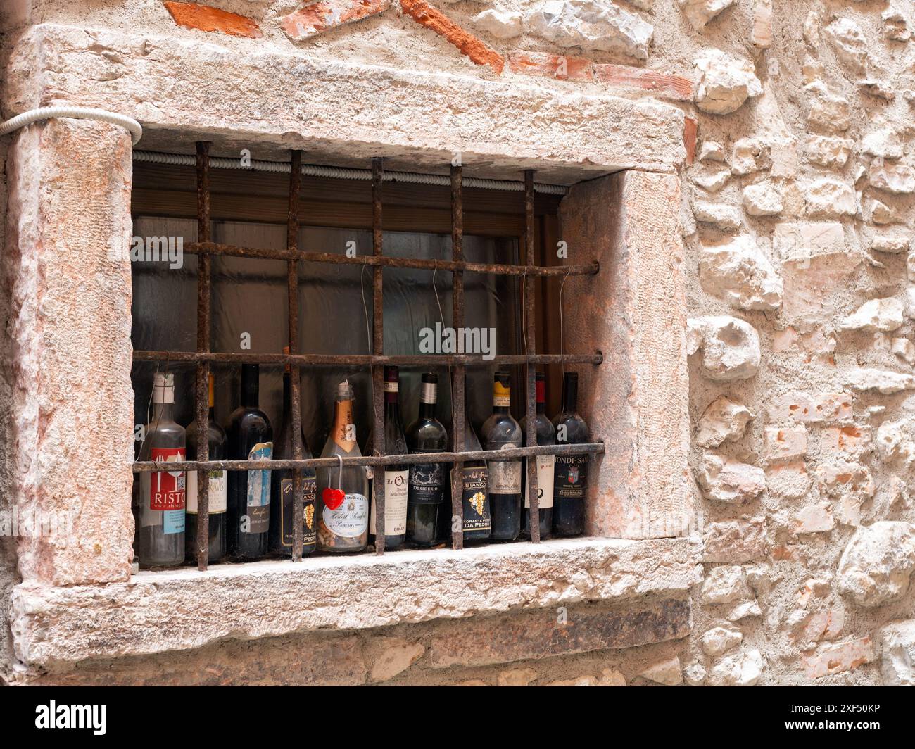 MALCESINE, ITALIE - 12 JUIN 2024 : vieilles bouteilles de vin vides dans une rangée dans une fenêtre dans la vieille ville Banque D'Images