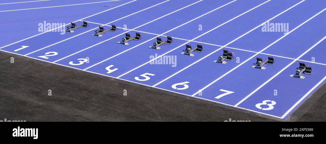Ligne de départ de la piste de course avec huit voies et des blocs de départ sur une piste d'athlétisme violette. Concepts de préparation, de compétition et de réussite Banque D'Images
