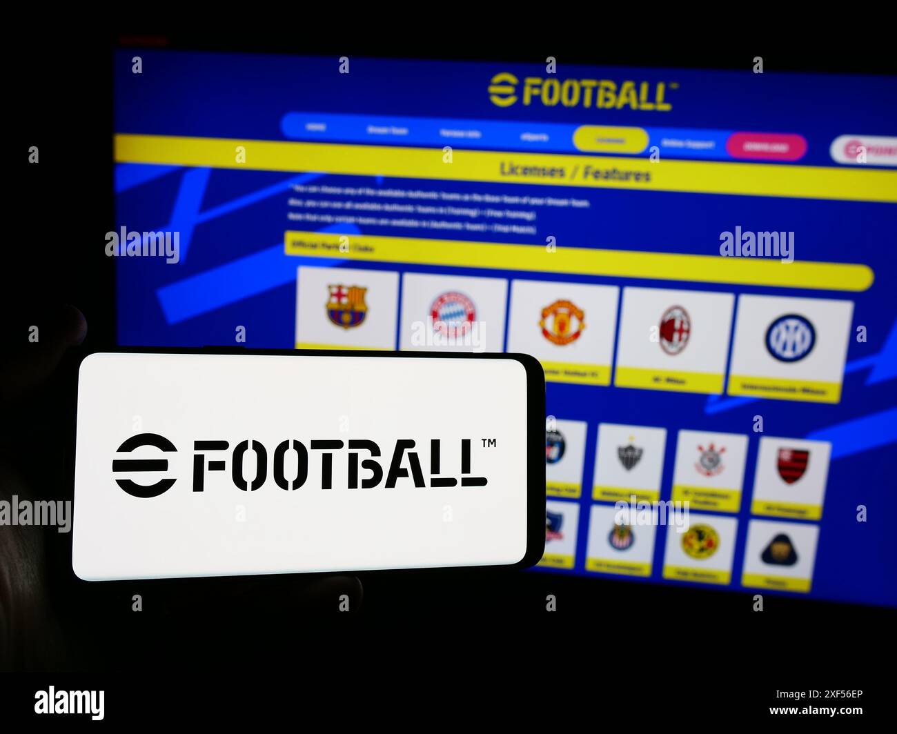 Personne tenant un smartphone avec le logo du jeu vidéo de football eFootball (Konami) en face du site Web. Concentrez-vous sur l'affichage du téléphone. Banque D'Images