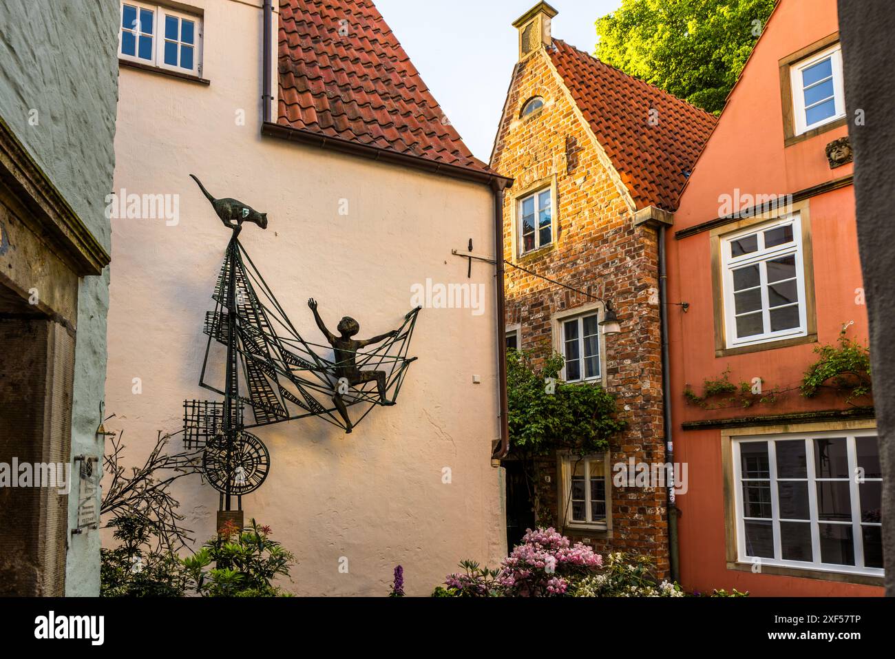 Une sculpture en fil métallique murale représente une figure assise les bras écartés à l'intérieur d'une structure en forme de cerf-volant, semblable à un filet. Un oiseau est perché au sommet. L'œuvre est accrochée à la façade d'une maison à pans de bois dans une ruelle historique de Brême, peut-être dans le quartier de Schnoor. Brême, Allemagne. Banque D'Images