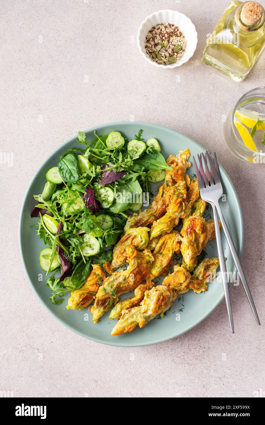 Fleurs de courgettes frites dans la pâte et mélanger la salade avec les concombres, vue de dessus Banque D'Images