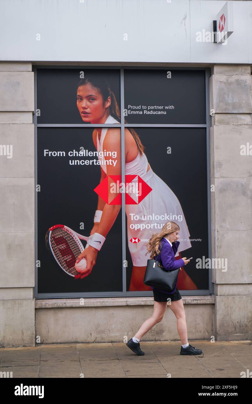 Wimbledon, Londres, Royaume-Uni 1er juillet 2024. Un piéton passe devant une succursale locale de la banque HSBC dans le centre-ville de Wimbledon. Avec une photo de la joueuse de tennis britannique Emma Raducanu en tant qu'ambassadrice mondiale de la marque. Credit : Amer Ghazzal/Alamy Live News Banque D'Images