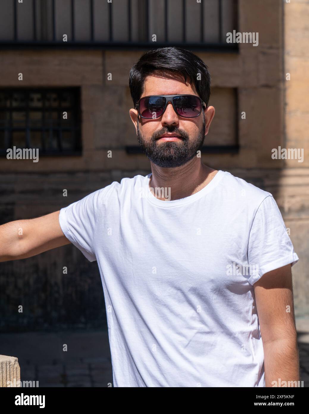 Portrait en gros plan d'un pakistanais moderne avec une barbe sombre, des vêtements légers et des lunettes de soleil Banque D'Images