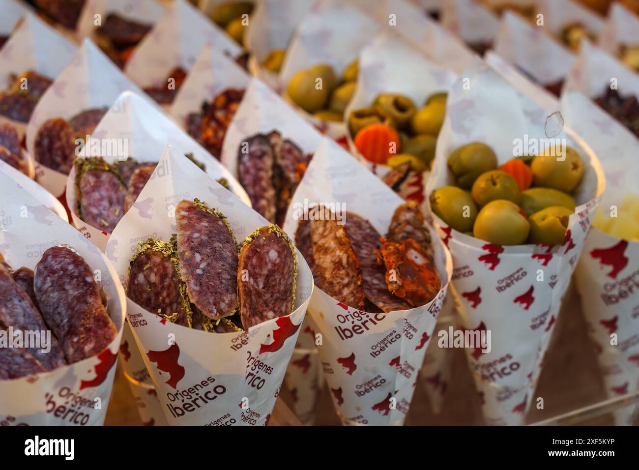 Séville, Espagne. 7 février 2024 - Salami espagnol et olives vendus en cônes de papier sur un marché de séville Banque D'Images