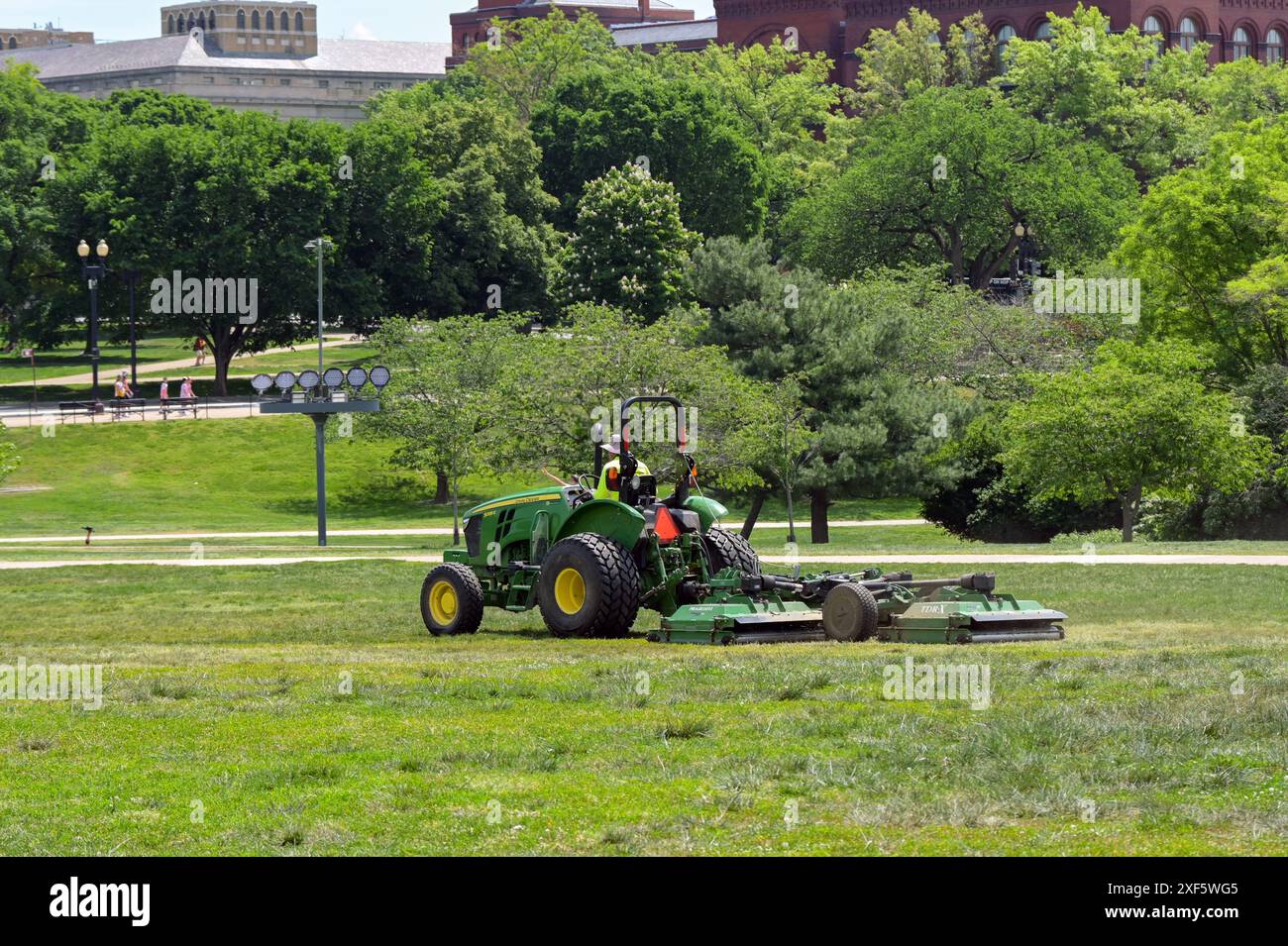 Washington DC, États-Unis - 30 mai 2024 : personne conduisant un tracteur avec une faucheuse attachée coupant l'herbe à Washington DC Banque D'Images