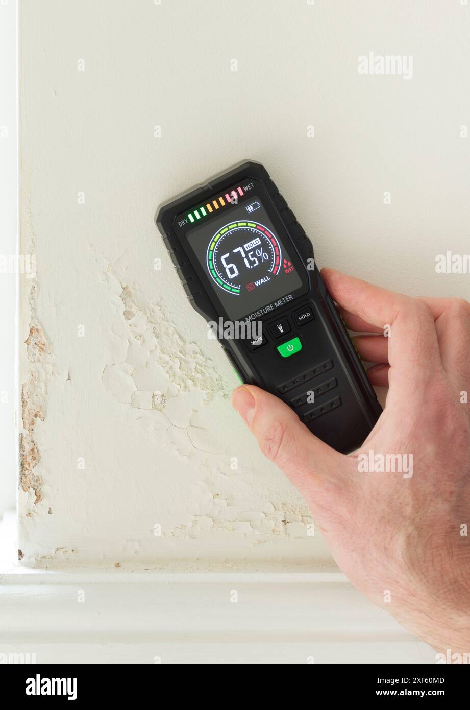 Détecteur d'humidité (compteur d'essai d'humidité) contre un mur avec l'humidité montante, lecture de la teneur élevée en humidité. Intérieur de la maison UK Banque D'Images