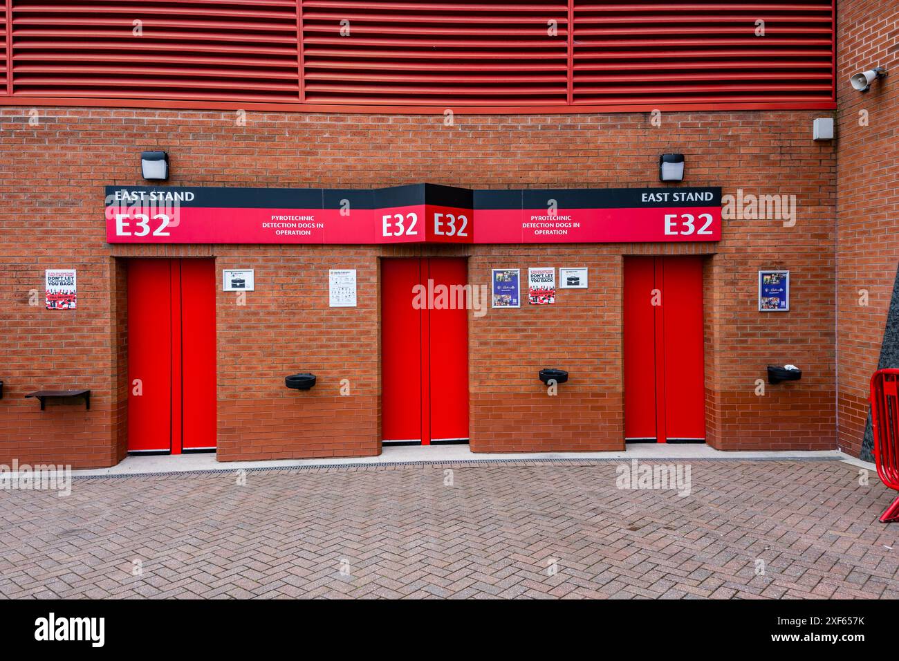 Manchester Trafford UK 29 juin 2024. Portes d'entrée du stade rouge vif étiquetées E32 sur un mur de briques, stand est, design urbain minimaliste. Banque D'Images