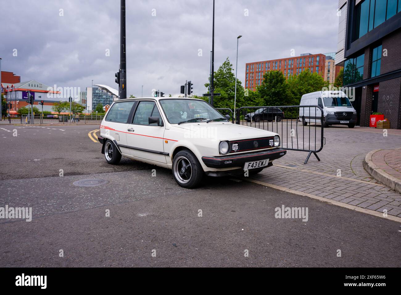Manchester Trafford UK 29 juin 2024. Voiture compacte Polo blanche vintage garée sur un coin de rue urbaine avec des bâtiments modernes en arrière-plan. Banque D'Images