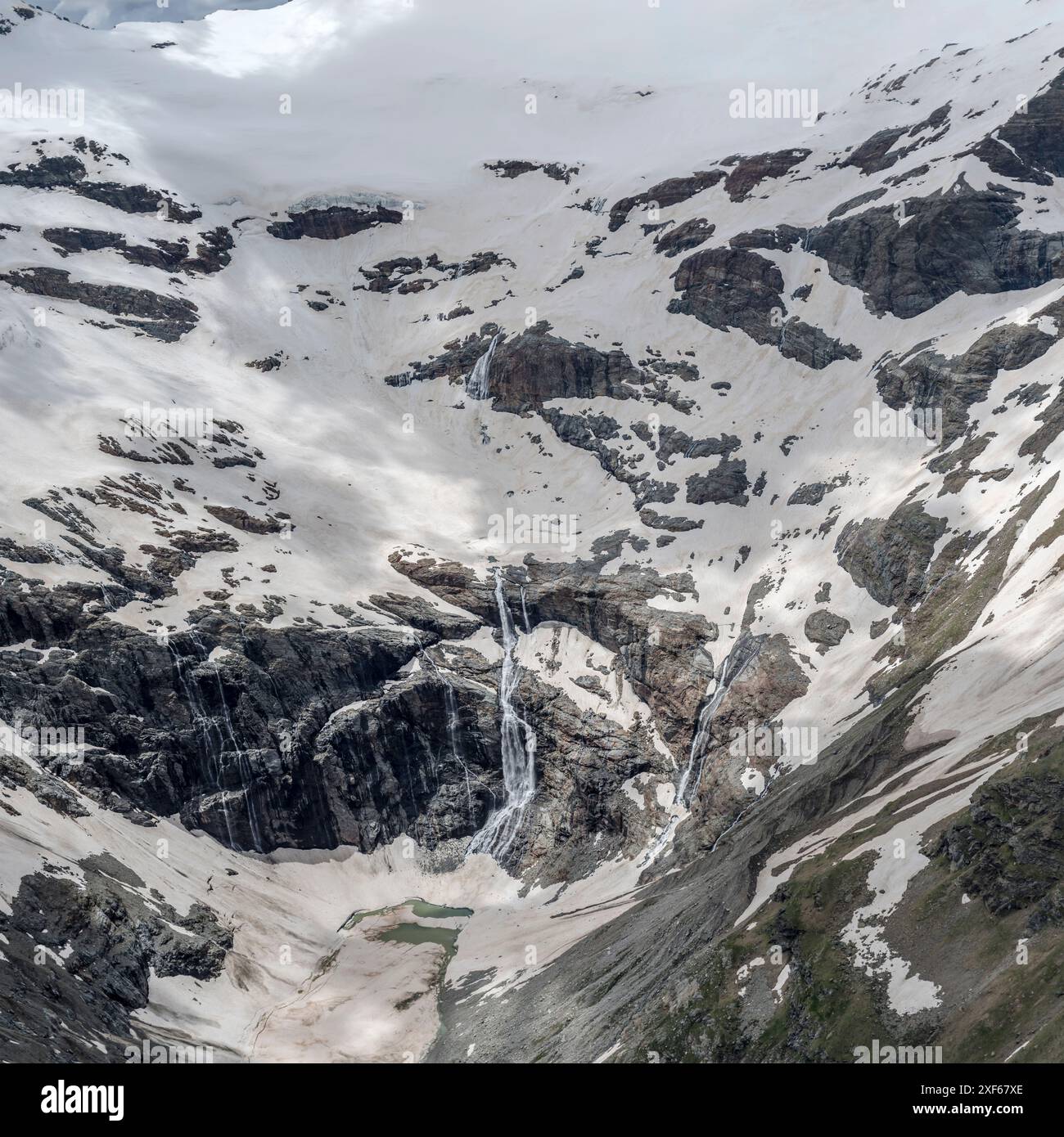 Paysage terrestre aérien, à partir d'un planeur, avec une cascade sous le glacier en fonte sur la chaîne de Bernina côté est, photographié d'en haut dans une lumière d'été brillante, Alp Banque D'Images