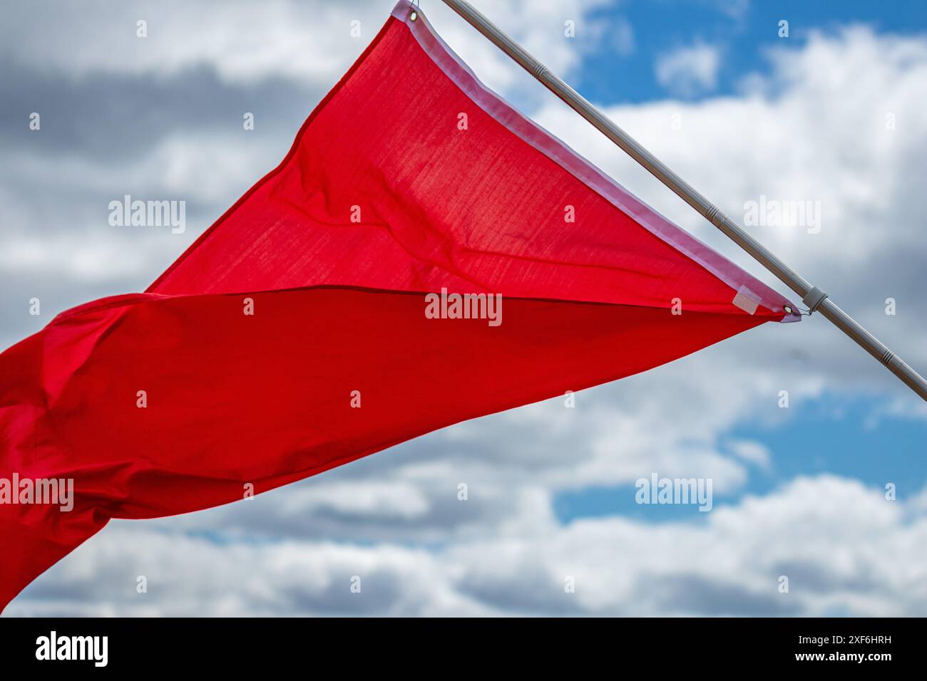 Drapeau d'avertissement rouge volant dans le vent contre le ciel bleu Banque D'Images