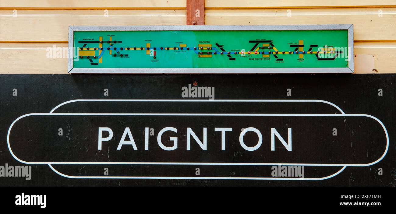 Panneau de gare de Paignton sur un mur en bois avec un indicateur de position de train au-dessus. Les lumières s'allument lorsqu'il se déplace le long de la piste. Banque D'Images