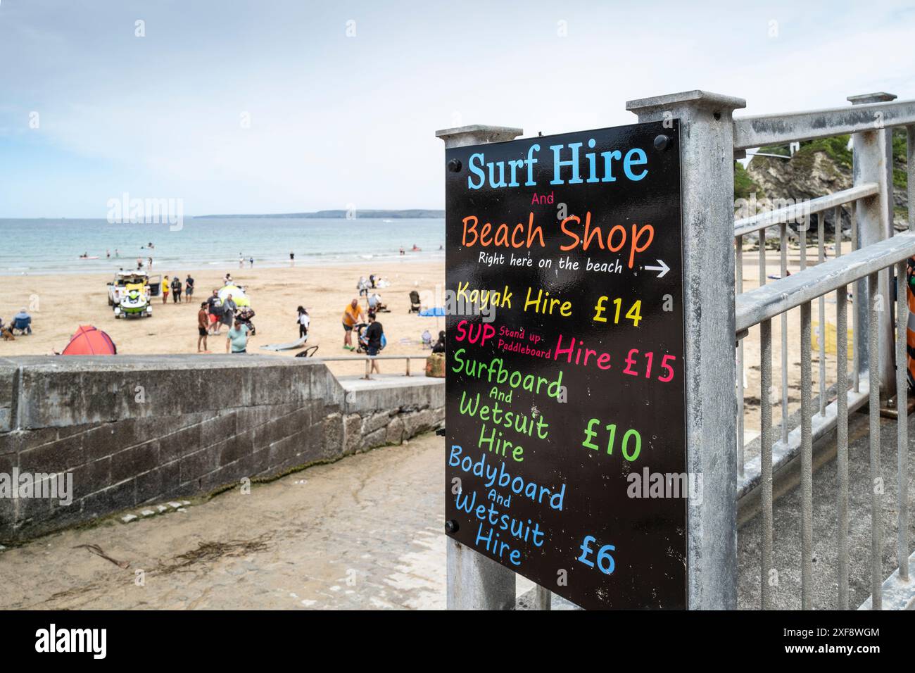 Une enseigne colorée et colorée annonçant des articles de location de surf et les prix de la boutique de plage à Towan Beach à Newquay en Cornouailles au Royaume-Uni. Banque D'Images