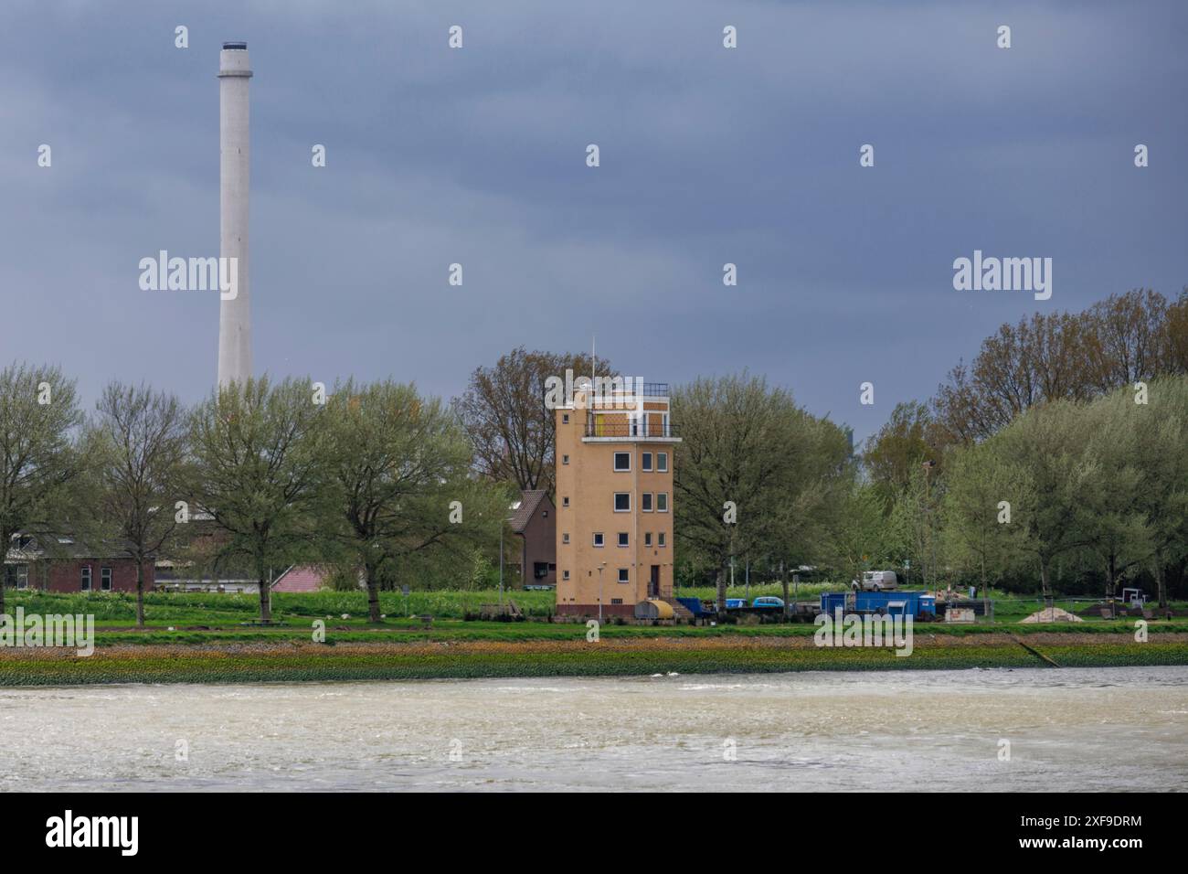 Maison au bord de la rivière avec une haute cheminée et des arbres, le ciel est nuageux, rotterdam, pays-bas Banque D'Images