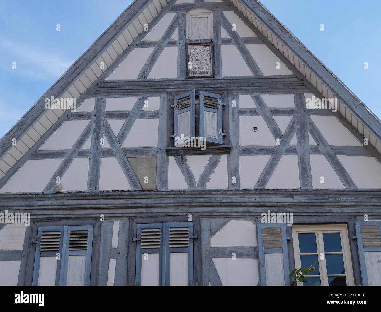 Maison à colombages avec structure en bois gris et volets bleus sous un ciel dégagé, Kandel, Palatinat, Allemagne Banque D'Images