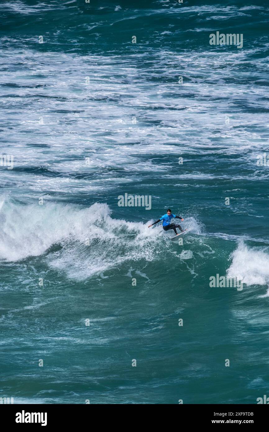 Un surfeur chevauchant une vague au large de la côte de Newquay en Cornouailles au Royaume-Uni. Banque D'Images