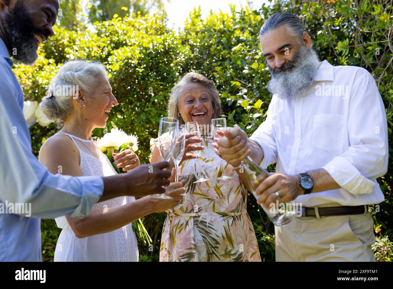 Célébration d'un mariage en plein air, amies âgées grillant avec des verres à champagne, souriant et appréciant Banque D'Images