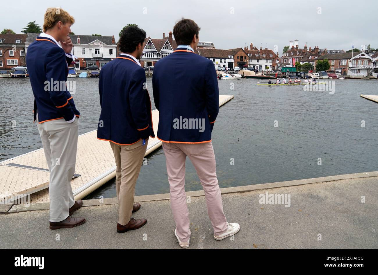 Les gens regardent du côté de la rivière tandis qu'une équipe d'aviron se dirige d'un ponton pour descendre à la ligne de départ le jour de l'ouverture de la Henley Royal Regatta 2024 le long de la Tamise, à Henley-on-Thames, Oxfordshire. Date de la photo : mardi 2 juillet 2024. Banque D'Images