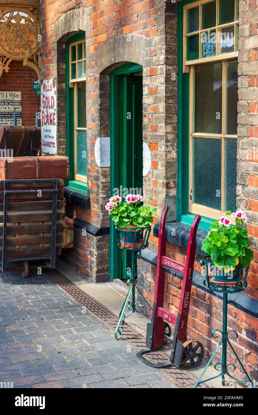 Quai et salle d'attente/billetterie à la gare de Sheringham avec vieux chariot à bagages, valises vintage et vieilles enseignes en émail Banque D'Images