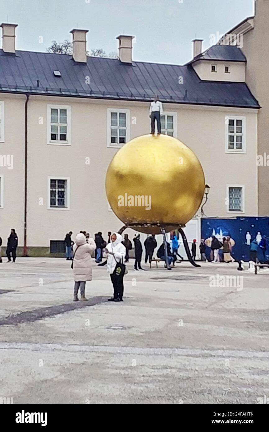 Salzbourg, Autriche - 23 décembre 2023 : sphère d'or avec un homme - sculpteur Stephan Balkenhol sur la place Kapitelplatz Banque D'Images