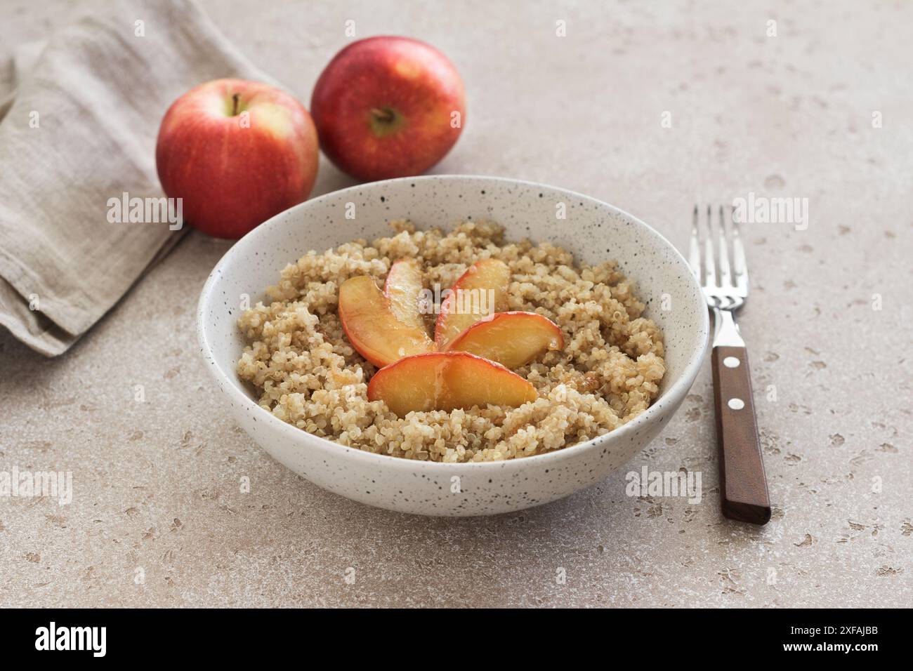 Quinoa avec tranche de pomme caramélisée sur un fond texturé beige. Plat sain végétalien Banque D'Images