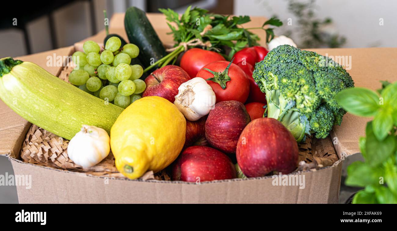 Vue en angle élevé des fruits et légumes cultivés à la ferme dans une boîte en carton. Banque D'Images