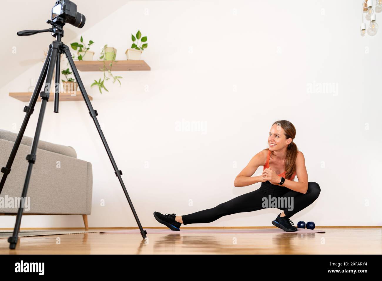 Femme brune athlétique prenant auto-vidéo pendant l'entraînement à domicile. Banque D'Images