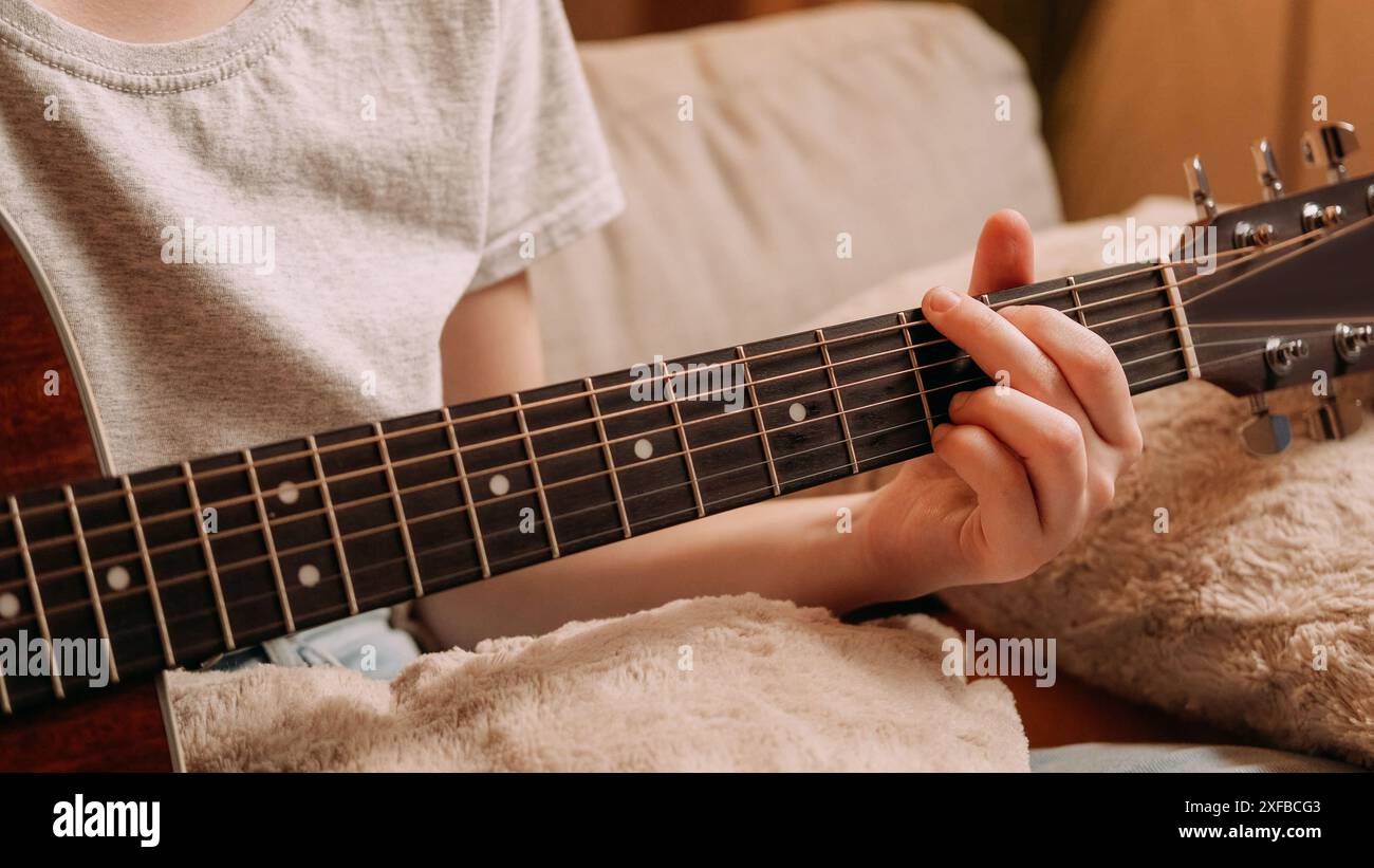 Passe-temps de guitare. Talent musical. Performances acoustiques. Femme méconnaissable jouant sur un instrument à cordes sur un canapé à la maison avec un espace libre. Banque D'Images