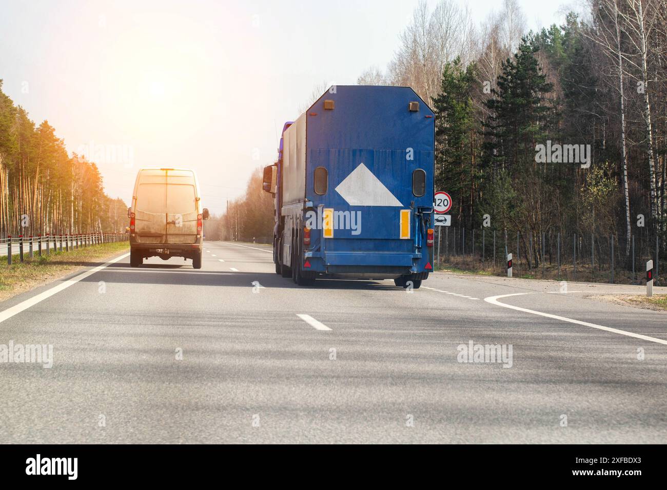 Un camion avec une semi-remorque pour le transport de verre transporte des marchandises le long de la route au printemps contre le soleil en toile de fond. Cargaison fragile, copie Banque D'Images