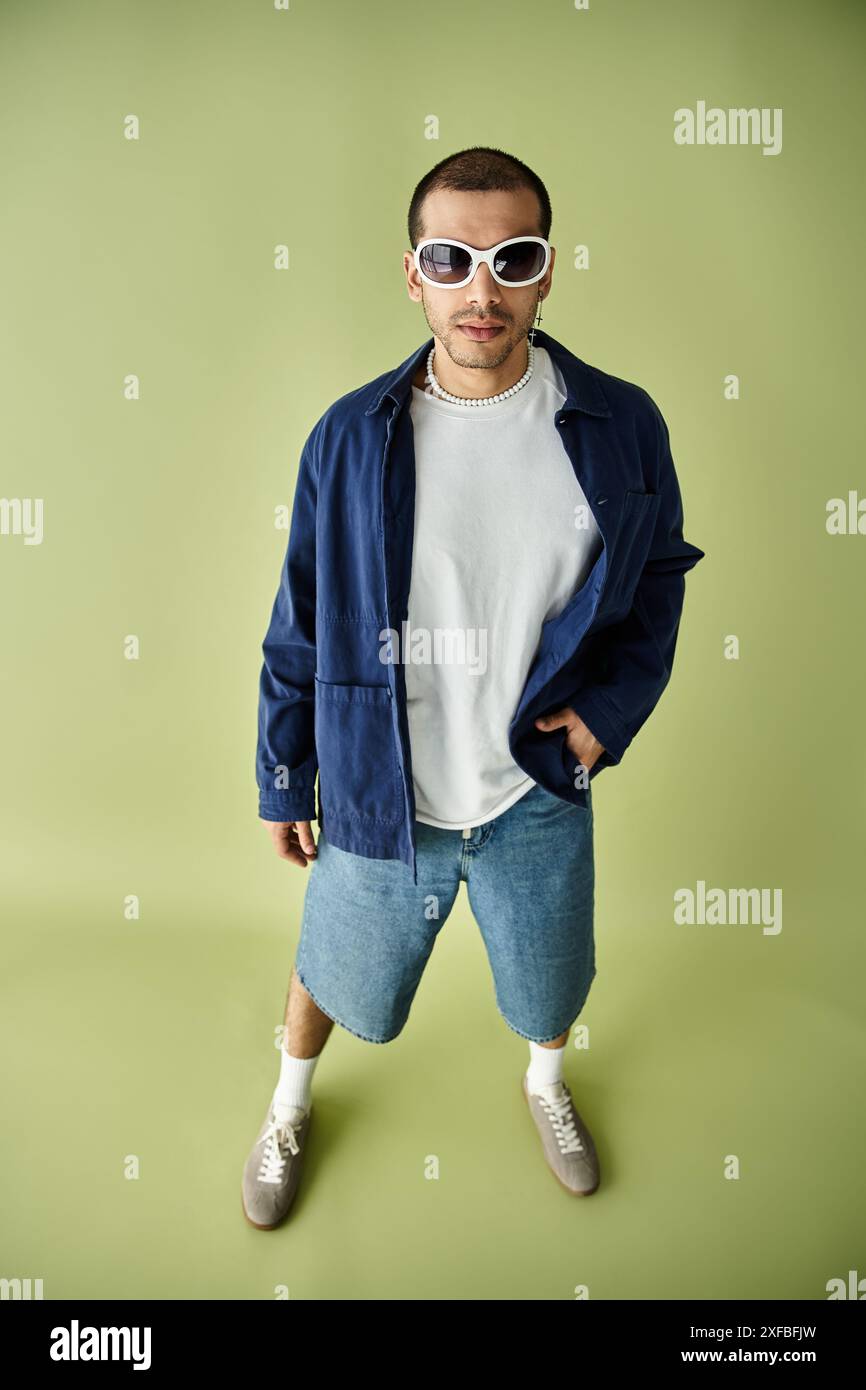 Un homme portant un t-shirt blanc et une veste bleue prend la pose. Banque D'Images