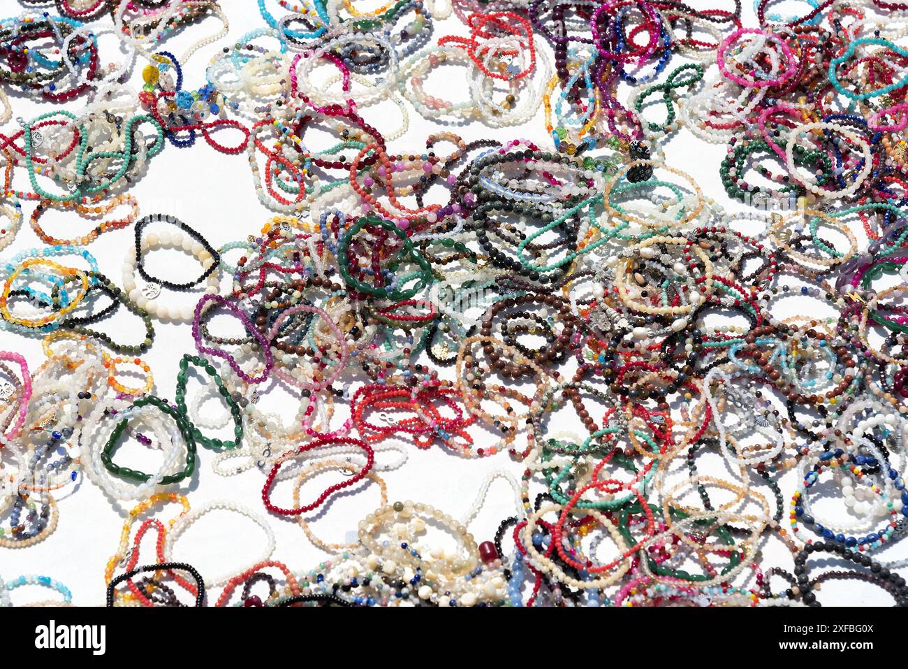 Bracelets colorés avec des perles en plastique étalés sur de la nappe blanche à vendre pour les touristes. Banque D'Images