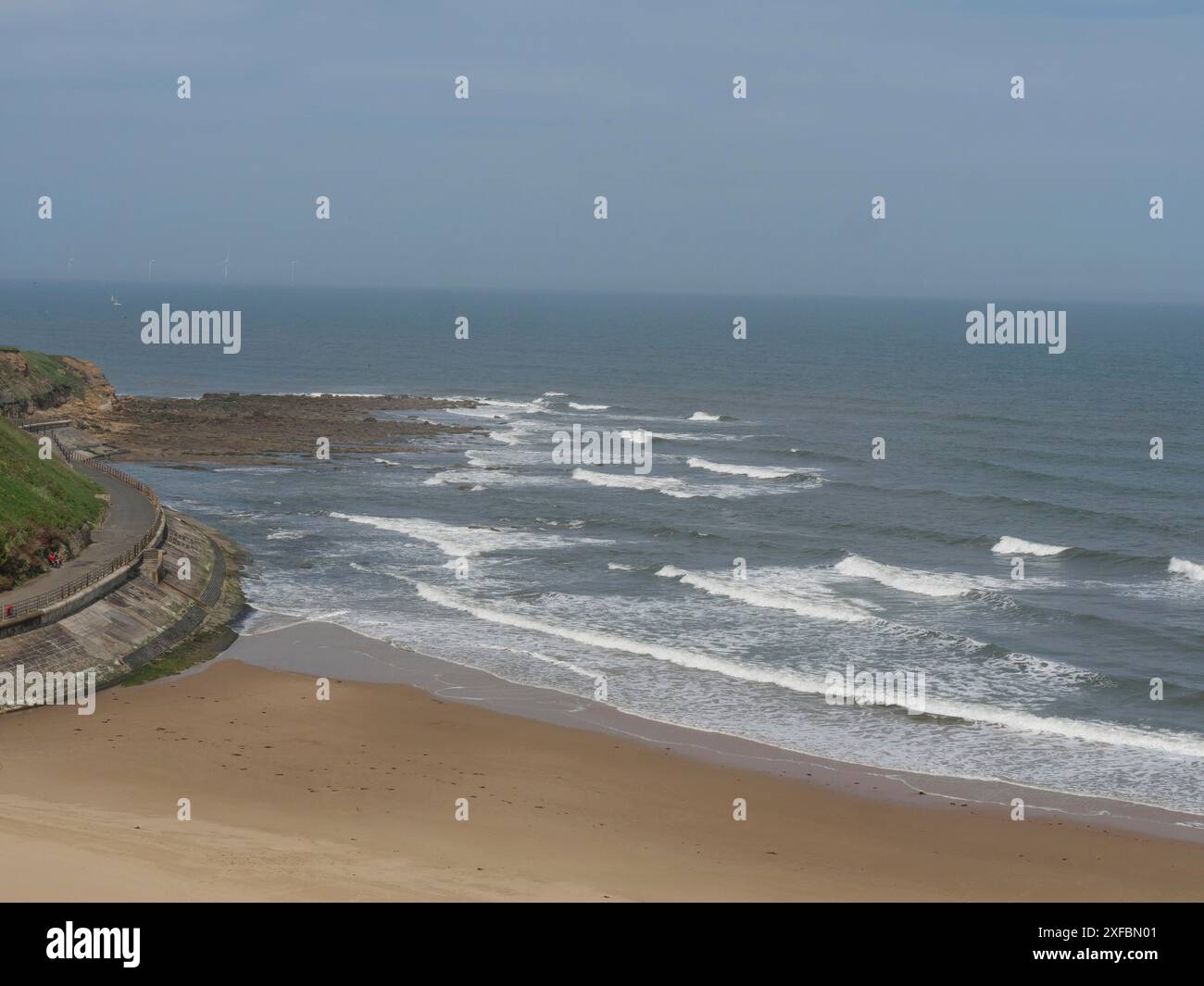 Une plage tranquille avec des vagues frappant le rivage sous un ciel clair, tynemouth, angleterre, royaume-uni Banque D'Images