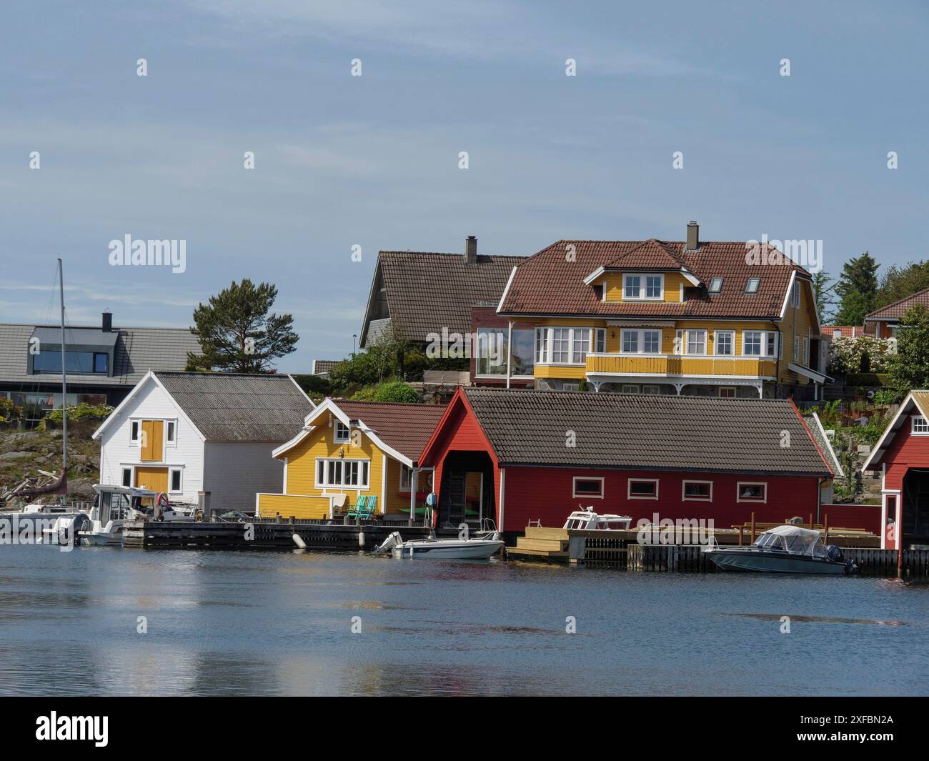 Pittoresques maisons côtières en rouge et jaune avec des bateaux sur l'eau, atmosphère paisible, stavanger, norvège Banque D'Images