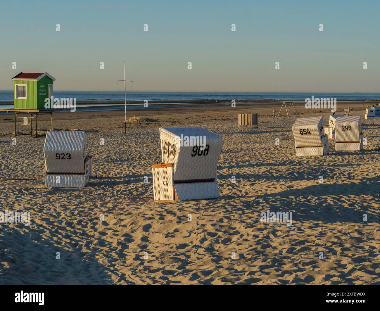 Plusieurs chaises de plage et un pavillon vert sur la plage au crépuscule Banque D'Images