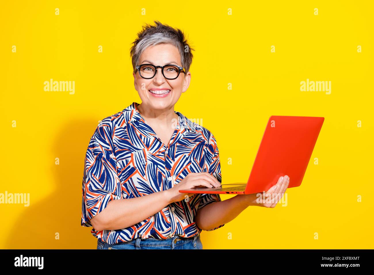 Portrait photo de belle femme retraitée tenir netbook porter tenue colorée à la mode isolé sur fond de couleur jaune Banque D'Images