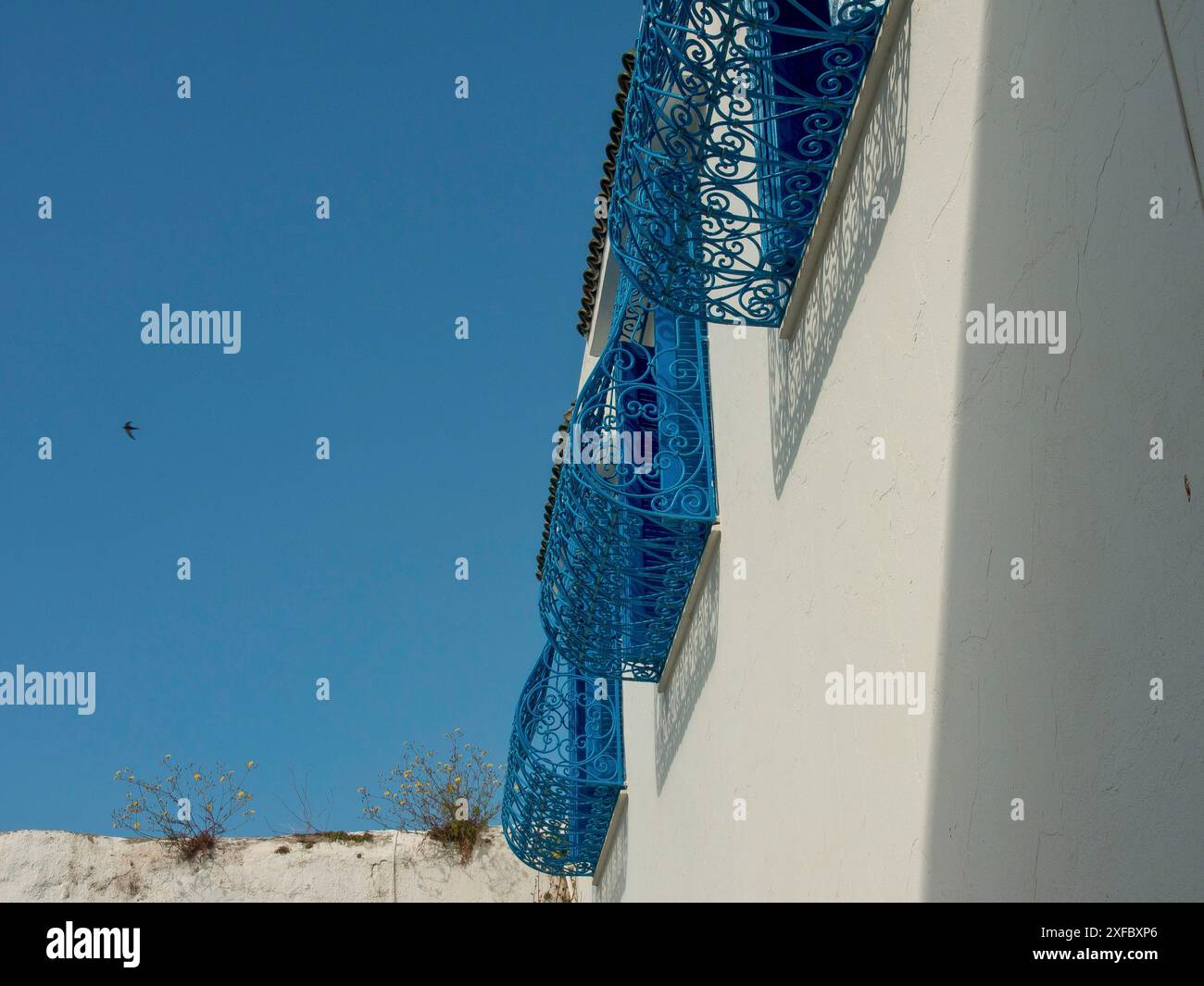 Balcon en fer forgé bleu dépasse d'un mur blanc, contre un ciel bleu, Tunis, Tunisie Banque D'Images