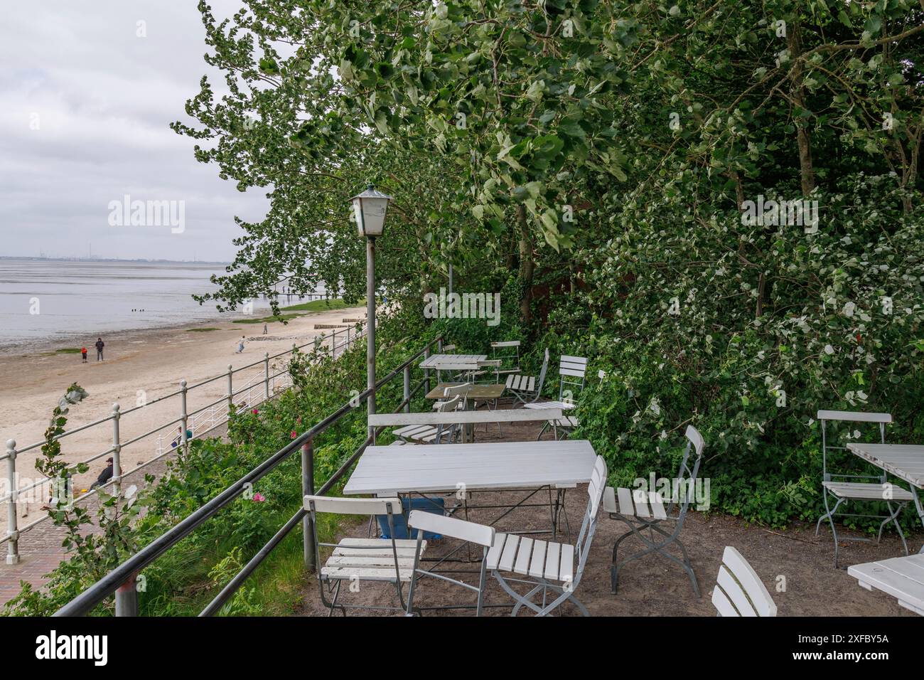 Tables et chaises blanches sur une terrasse entourée de verdure avec vue sur la mer, dangast, varel, allemagne Banque D'Images