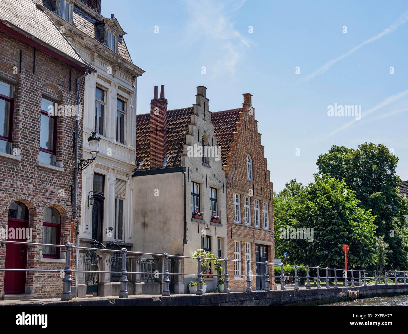 Bâtiments le long d'un canal paisible sous un ciel clair, Bruges, Flandre, Belgique Banque D'Images