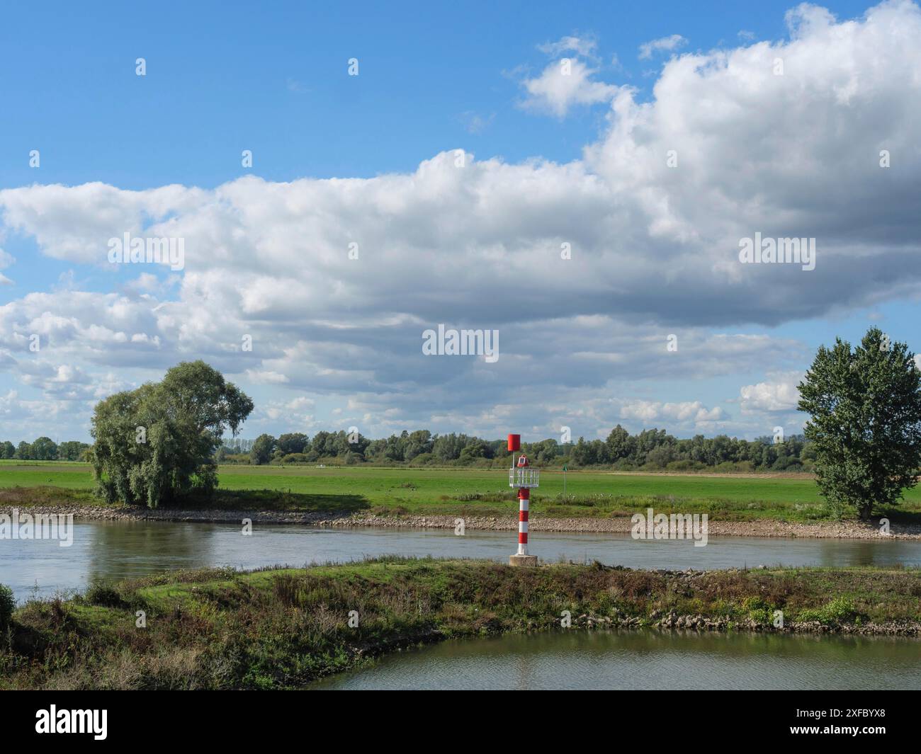 Un paysage fluvial pittoresque avec des prairies verdoyantes et des arbres sous un ciel bleu et blanc, marqué par un panneau rouge et blanc dans l'eau, zutphen Banque D'Images