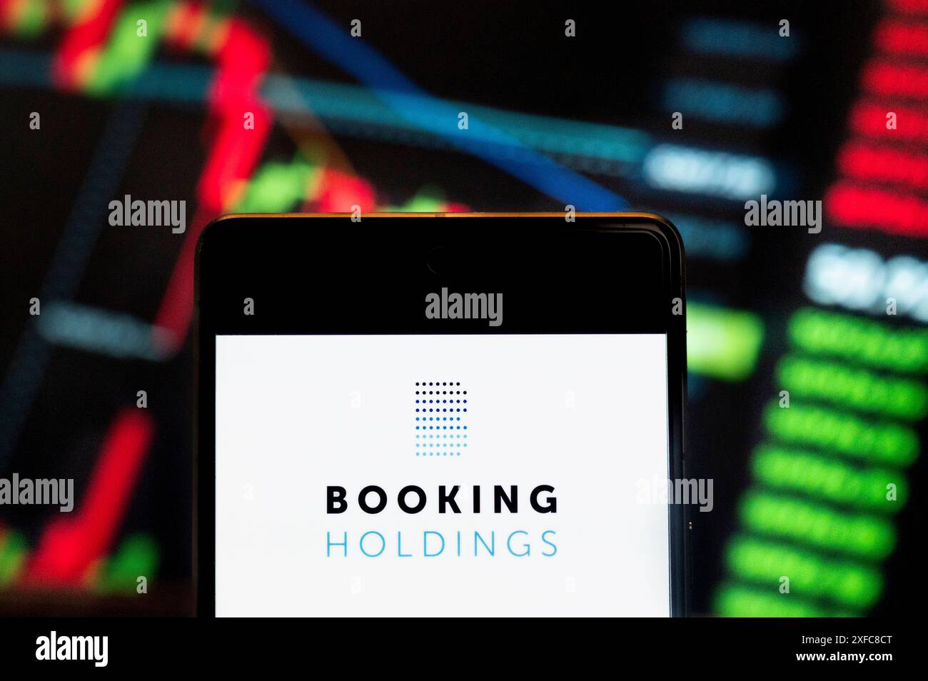 Dans cette illustration photo, le logo du leader mondial de la réservation de voyage en ligne Holdings (NASDAQ : BKNG) vu affiché sur un smartphone avec un graphique de l'indice boursier économique en arrière-plan. Banque D'Images