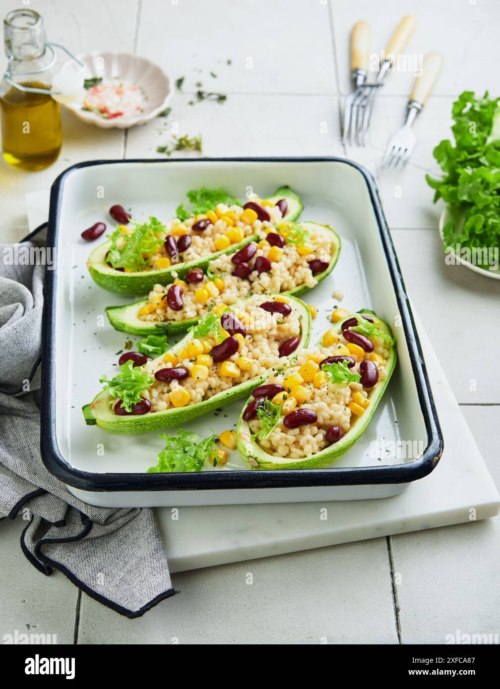 Courgettes farcies au petitim, haricots rouges, maïs au basilic et sauce cuite sur un vieux fond de tuiles craquelées. Vue de dessus. Banque D'Images