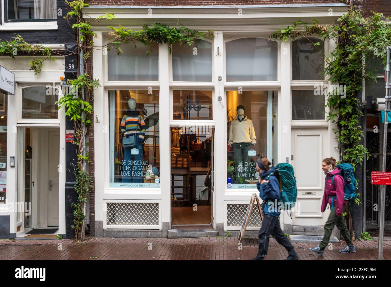Deux jeunes touristes avec des sacs à dos passant la boutique BrandMission à Haarlemmerstraat, Amsterdam. Banque D'Images