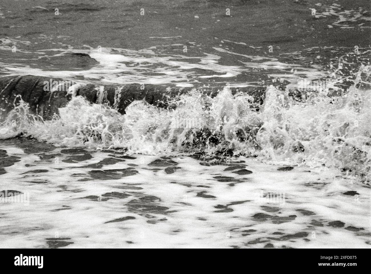 Les vagues de la mer du Nord se brisent sur la plage de sable de Sutton on Sea, tourné sur film noir et blanc Banque D'Images