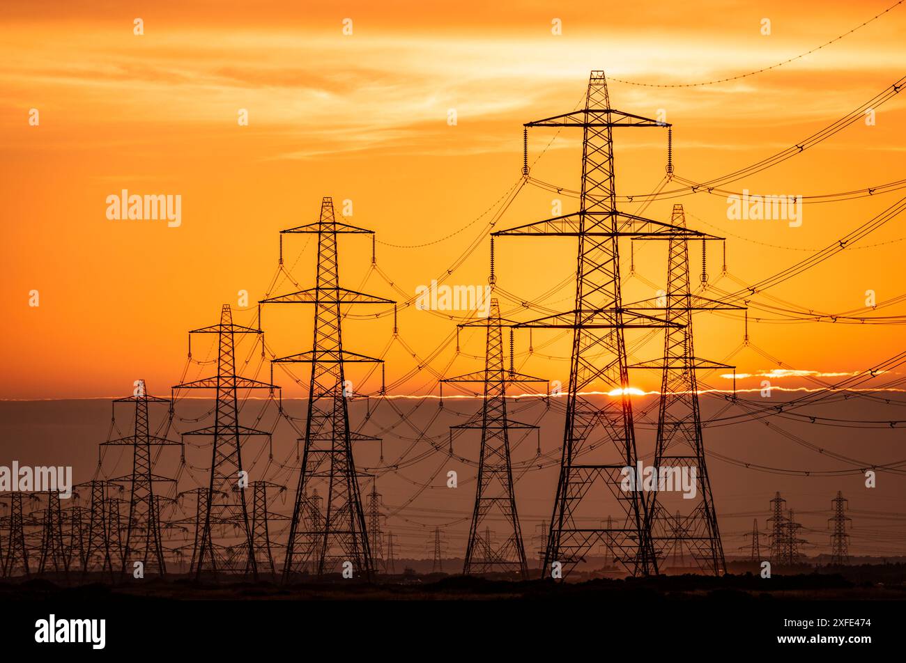 Coucher de soleil derrière les lignes électriques partant de la centrale électrique Dungeness sur la côte sud-est de l'Angleterre du Kent Banque D'Images