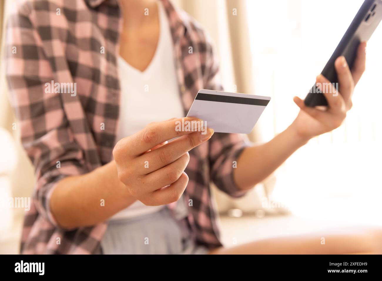Tenant carte de crédit et smartphone, femme faisant l'achat en ligne à la maison Banque D'Images Tenant carte de crédit et smartphone, femme faisant l'achat en ligne à la maison Banque D'Images